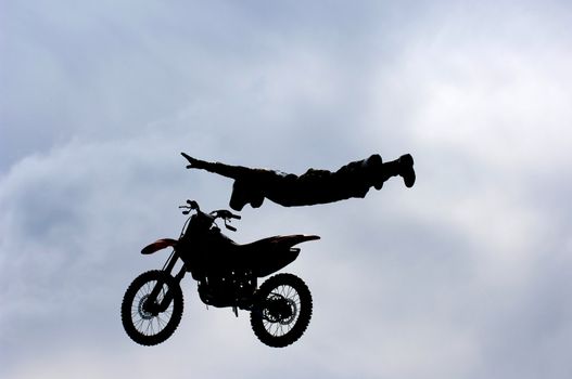 A freestyle motocross rider performs a trick (superman) during a competition.