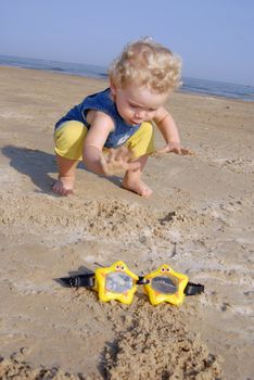 Baby girl on the beach about to take her swimming glasses star shaped.