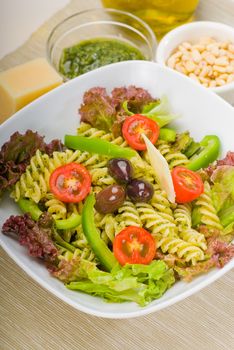 fresh healthy homemade italian fusilli pasta salad with parmesan cheese,pachino cherry tomatoes, black olives and mix vegetables ,dressed with extra-virgin olive oil and pesto sauce