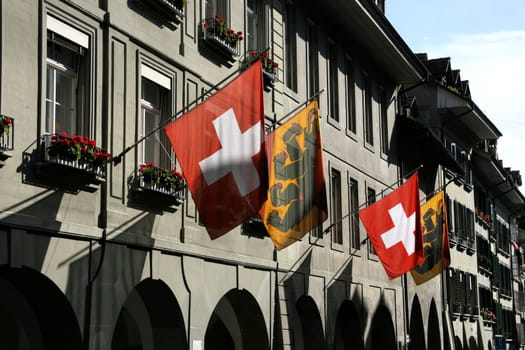 Swiss flag and Bern flag in Berne, Switzerland. Old town street.