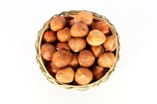 Hazelnuts in a round basket, isolated on white