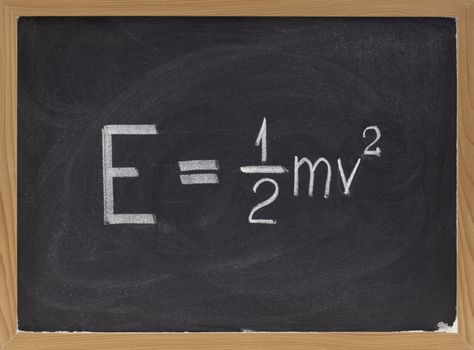 kinetic energy equation of classical Newtonian mechanics connecting it to mass and velocity of a point object  - white chalk handwriting on blackboard