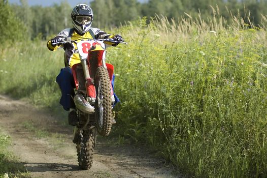 A motocross rider making wheelies on his bike