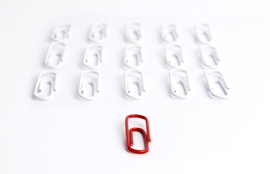 Conceptual idea of leadership. Red clip in focus, leading a group of aligned white clips