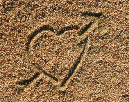 Heart with the Cupid arrow drawn in the sand. Love background
