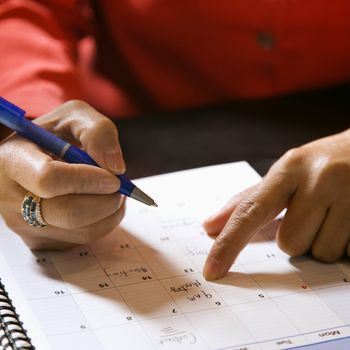 Close-up of businesswoman writing in appointment calendar.