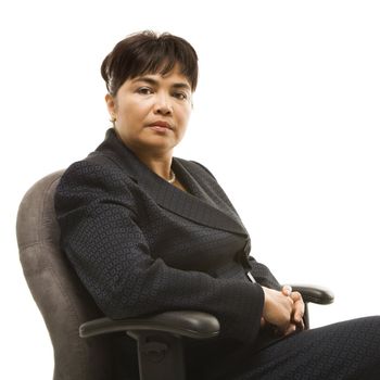 Filipino middle-aged businesswoman sitting in office chair against white background.