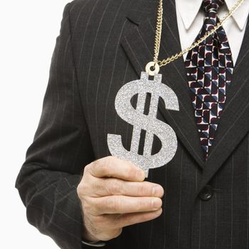 Close-up of Caucasian middle-aged businessman wearing chain necklace with oversized dollar sign.