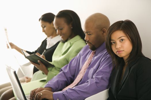 Vietnamese businesswoman sitting looking at viewer with others in background.