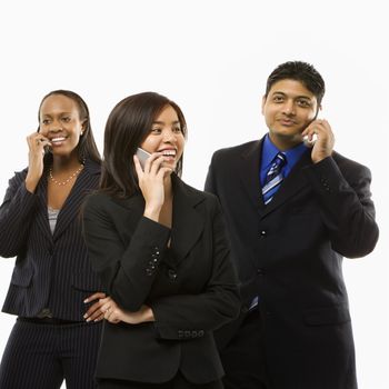 Multi-ethnic businesswomen and businessman standing talking on cell phones.