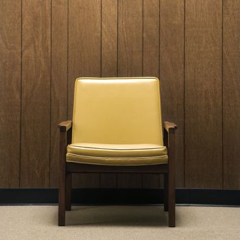 Retro chair against wood paneling in office.