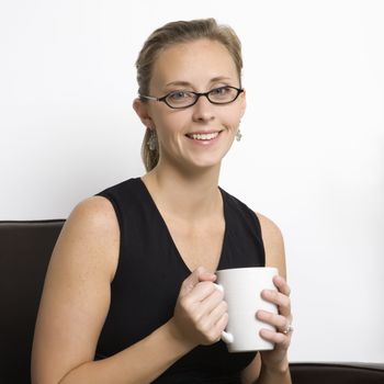 Caucasian mid-adult woman wearing eyeglasses holding coffee cup and looking at viewer.