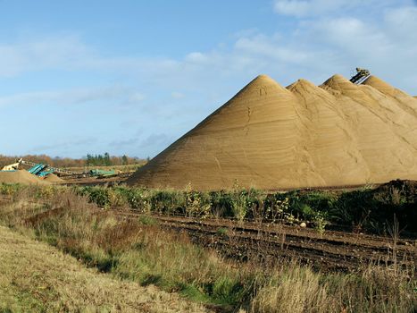 Yes, we have pyramids in Denmark, too. I saw these huge gravel heaps at a pit side, and couldn't resist the very beautiful structure from millions of years old sediments reflecting in the sunshine. The picture also shows the top of the conveyor belt (a pater noster band) and the heavy machinery in the background. Very fine picture for illustrating books or articles about the basic raw materials for a lot of industries, road building, and for geography etc.