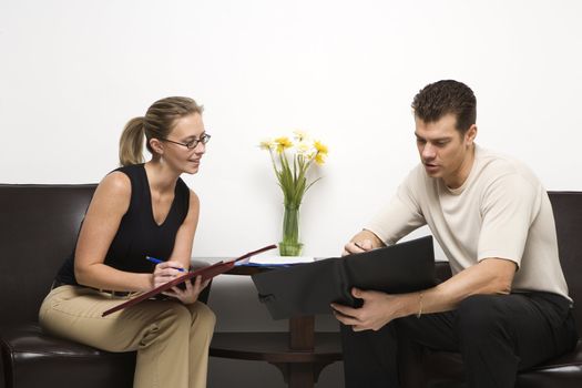 Caucasian mid-adult man and woman sitting looking at portfolios.