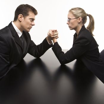 Side view of Caucasian mid-adult businessman and businesswoman arm wrestling on table.