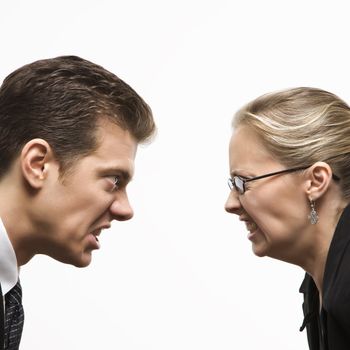 Close-up of Caucasian mid-adult man and woman staring at each other with hostile expressions.