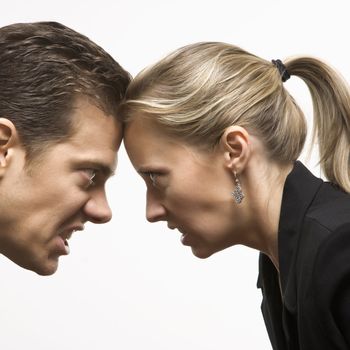 Caucasian mid-adult man and woman with foreheads together staring at each other with hostile expressions.