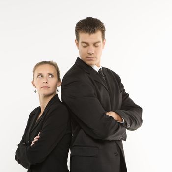 Caucasian mid-adult businessman and woman standing back to back looking at each other.