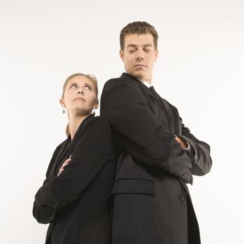Caucasian mid-adult businessman and woman standing back to back looking at each other.