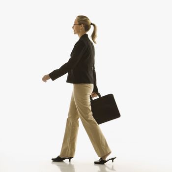 Mid-adult Caucasian businesswoman walking and carrying briefcase.