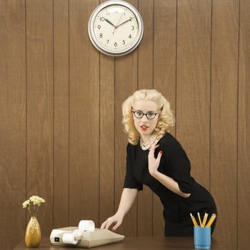 Mid-adult Caucasian female wearing vintage outfit in office touching calculator.