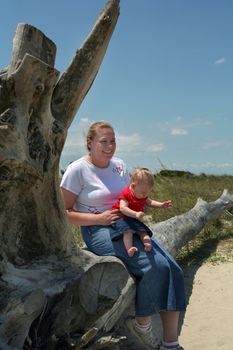 Mother and daughter sitting on a log at the beach