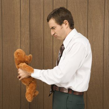 Mid-adult Caucasian male holding a stuffed animal and looking upset.