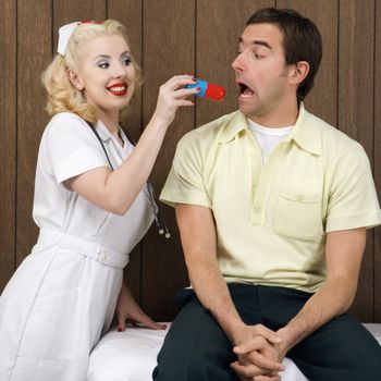 Caucasian mid-adult female nurse giving mid-adult man giant pill.