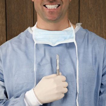 Mid-adult Caucasian male surgeon holding oversized syringe and smiling maniacally.