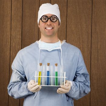 Mid-adult Caucasian male surgeon wearing thick glasses and holding test tube tray.