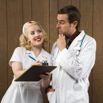 Mid-adult Caucasian female nurse smiling at male doctor making facial expression.
