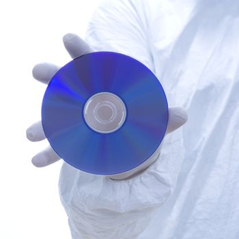 Close-up of man in biohazard suit and latex gloves holding compact disc.