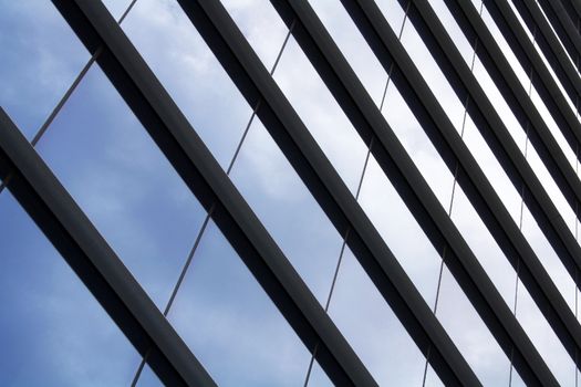 Modern glass facade reflecting blue sky with clouds