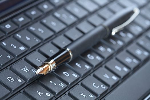 Closeup of fountain pen lying on black computer keyboard