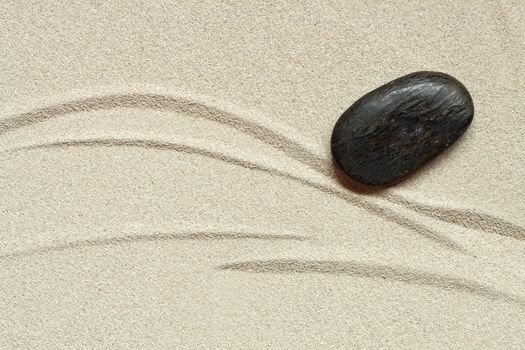 Abstract background with black stone lying on sand