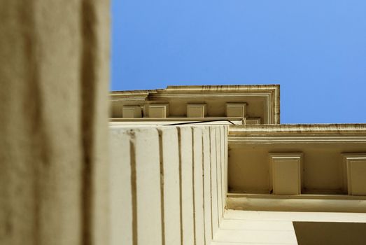 Architectural detail of an antique building.  Bottom View of column and ceiling. Blue sky background