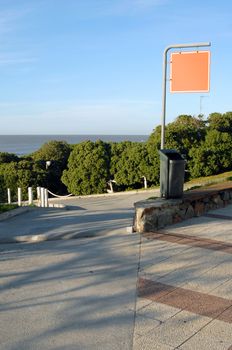 Urbanscape of a street with an empty signage. Suitable for insert text, image or design. Vegetation, beach and blue sky on the background.