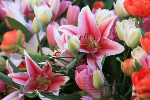 A flower arrangement made from pink lilies and orange tulips