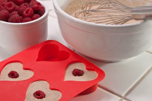 Batter bowl and raspberries with heart shaped muffin pan