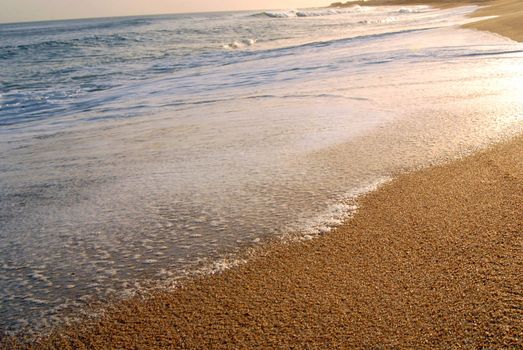 Wave foam and golden sand on the shore. Punta del Este beach