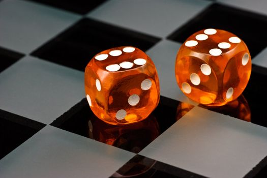 Two cube amber dice with rounded corners on checkered board