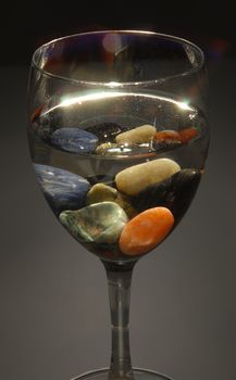 Colored stones in a glass of water. Concepts of altenative therapies, zen life and harmony.