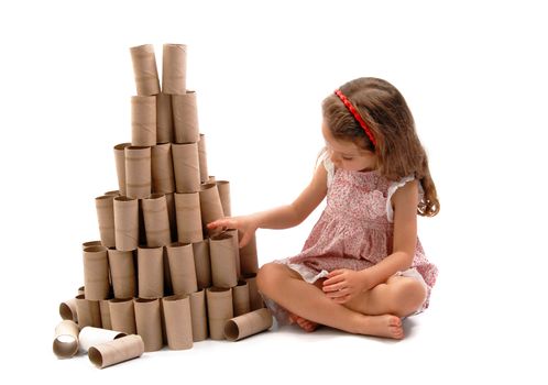 Little girl making a Christmas Tree with cardboard rolls of toilet paper. White background