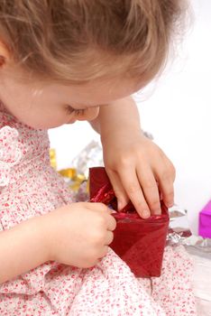 Little girl opening Christmas presents.  White background