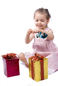 Happy little girl about to open her Christmas presents, playing with a blue ribbon. White background