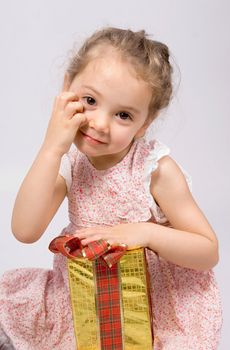 Little girl with a Christmas present looking at the camera. White background