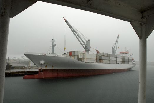 Huge container cargo ship heading for port. Cloudy sky background