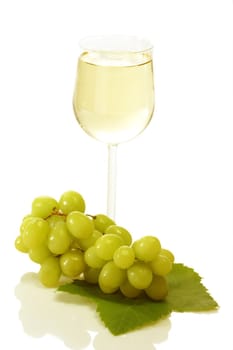 Glass of white wine with grapes and leaves on white background