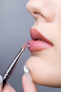 applying liquid gloss at the lips, moisturizing them