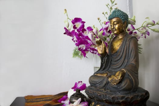 A traditional Chinese Buddha statue with flower at background.